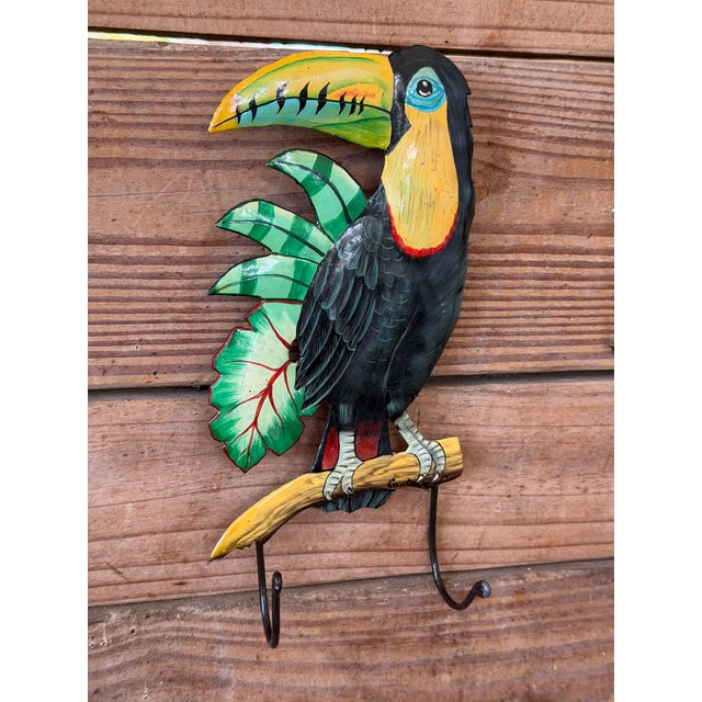 Charming vintage tropical wall hook featuring a colorful toucan perched on a branch with lush green foliage. The piece is...