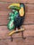 Charming vintage tropical wall hook featuring a colorful toucan perched on a branch with lush green foliage. The piece is...