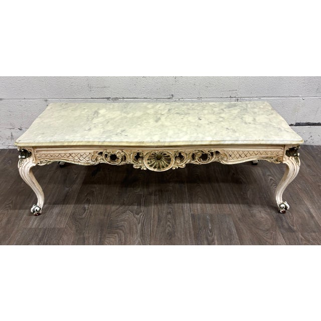 This is a vintage Italian Rococo Revival coffee table featuring a thick creamy white marble top over an ornately carved...