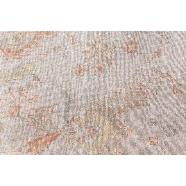 This stunning antique Oushak rug (size adjusted) exemplifies the refined artistry of Turkish weaving traditions from the...