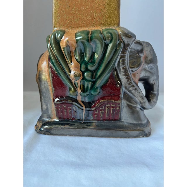 Vintage pair of glazed ceramic elephant sculptures in subtle shades of green, burgundy, and gold. Sculptures are just over...