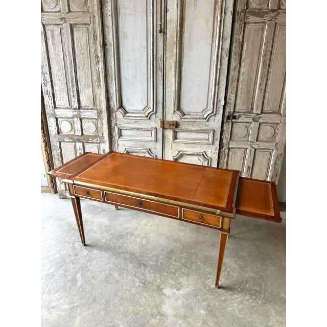 Mid-20th century directoire-style flat desk in cherry wood. Camel leather top embossed with a pattern around the edge....