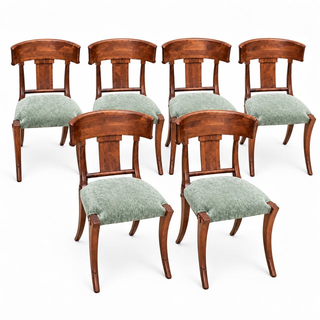 A striking set of six walnut Klismos dining chairs featuring beautifully figured wood grain, sweeping curved backrests,...