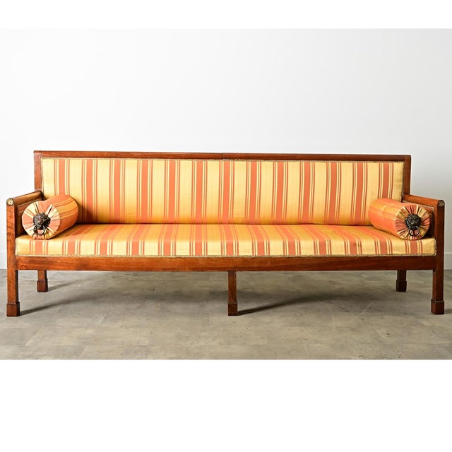This massive French, Directoire period 19th century fruitwood bench/settee is upholstered in a dazzling striped satin...