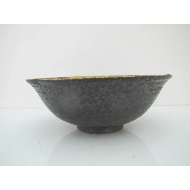 Beautiful Asian studio pottery bowl in dark gray tone with gold metallic rim and lustrous dainty flower design at center....