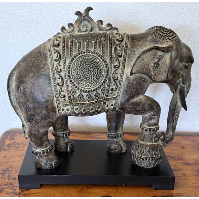 This Indian-style ornate resin elephant figure features intricate details and stands on a wood pedestal base. It measures...