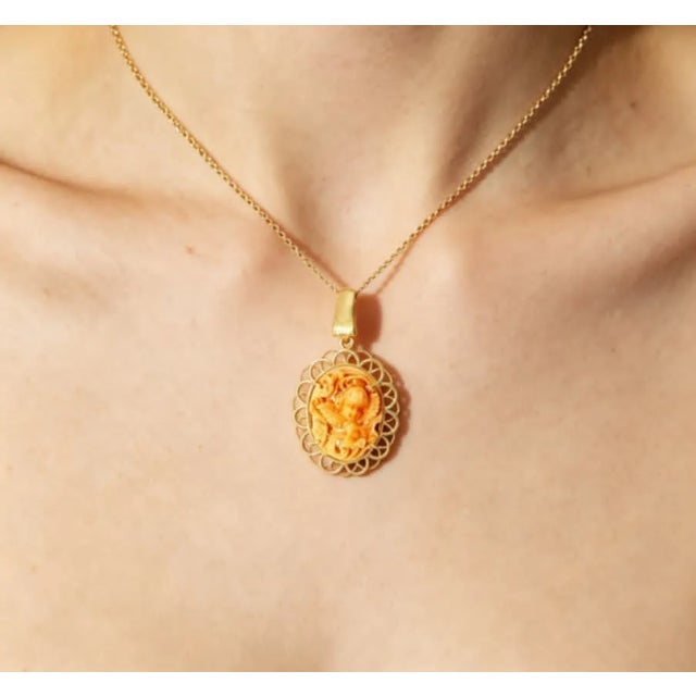 Material: 14K Yellow Gold Stone: Genuine Oval Coral Design: Angel with Floral Motif in Filigree Setting Dimensions: 32 mm...