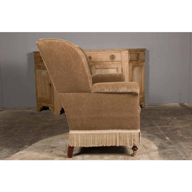 A vintage English wingback loveseat / settee with brown upholstery, out-scrolling arms and casters. This vintage English...