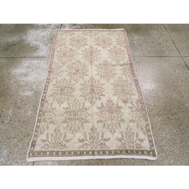 A vintage Turkish Anatolian throw rug. A taupe and beige dot pattern narrow border frames the oyster field of this...