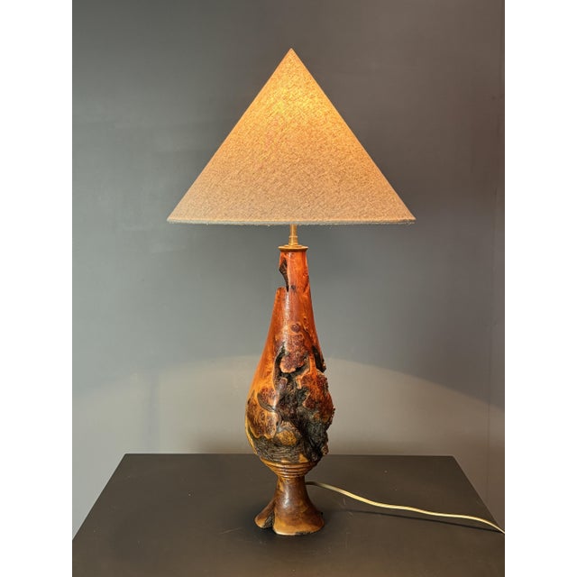 A striking sculptural table lamp from 1960s France, hand-turned from a single dense burl wood trunk. The form follows the...