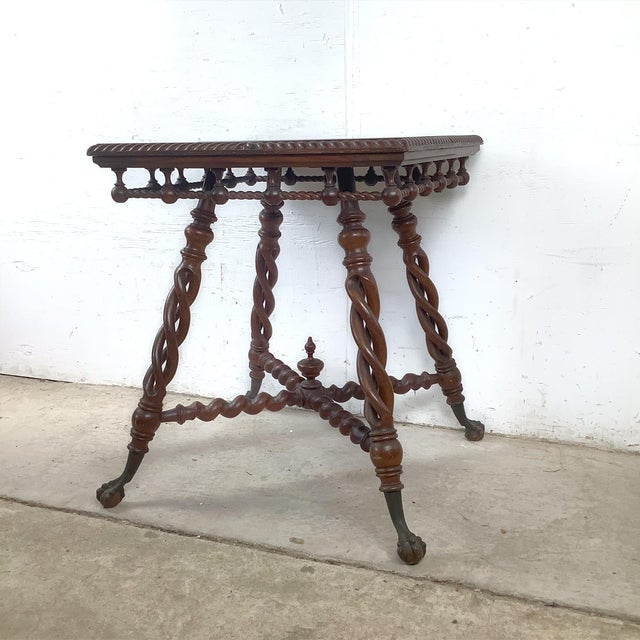 A commanding showcase of historic woodwork, this antique accent table serves as a dramatic structural anchor for any...