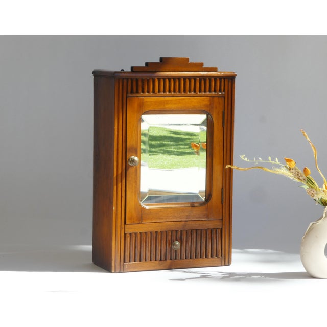 A beautiful antique Art Deco style cabinet with a beveled mirror. The wooden cabinet is made out of oak and is lacquered....