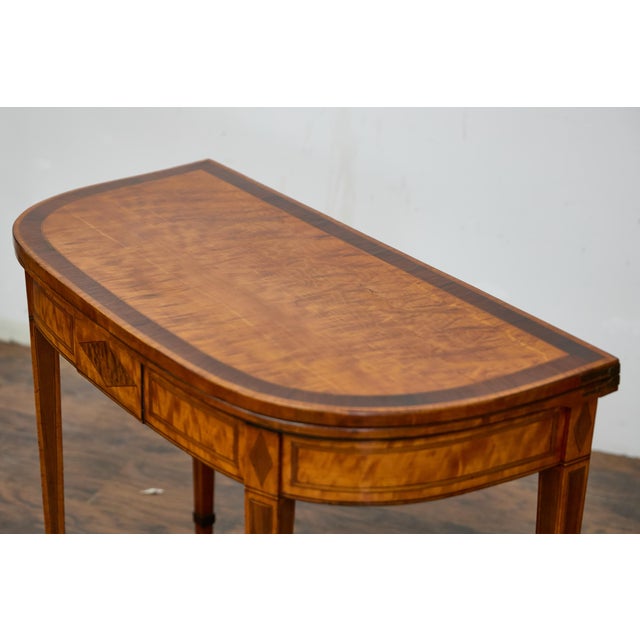 An English Neoclassical demi-lune game table from the 19th century with flip top and inlaid diamond décor. This English...