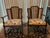 A charming pair of vintage rocking armchairs featuring woven cane backs, turned legs, and classic floral and bamboo...