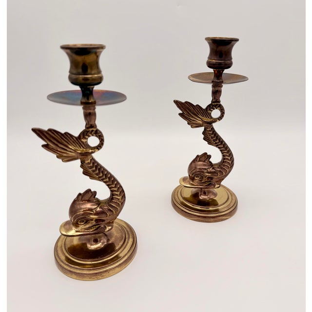Elevate your space with this striking pair of vintage patinated brass candlestick holders, sculpted in an elegant dolphin...