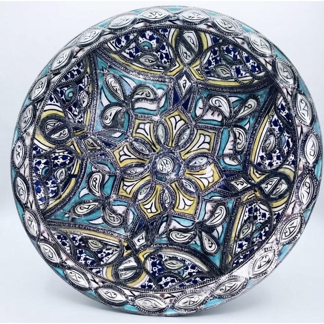EDITORIAL DESCRIPTION This Moroccan wall plate layers three artisan traditions hand-thrown pottery, brush-painted ceramic,...