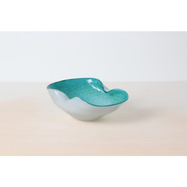 A hand-blown Murano art glass bowl featuring a white cased base with a translucent aqua bullicante rim and sculptural...
