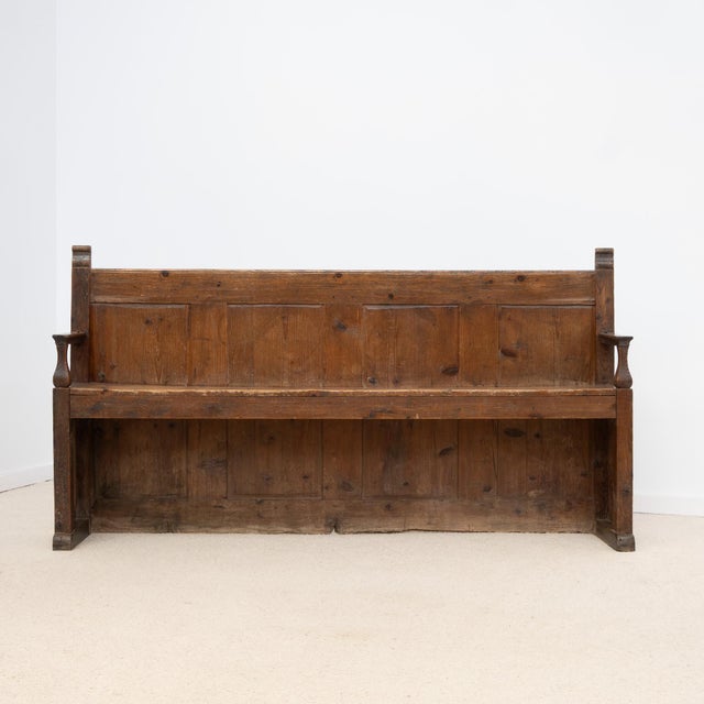 Antique wooden bench dating from the 19th century, with a tall back made of vertical panels. It features two armrests and...
