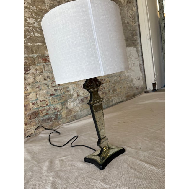 An elegant and sculptural silver table lamp featuring an ornately etched body with classic detailing and a substantial,...