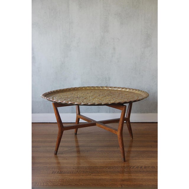 This exquisite hand-hammered brass Moroccan tray features a stunning mid-century mahogany base complemented by four...