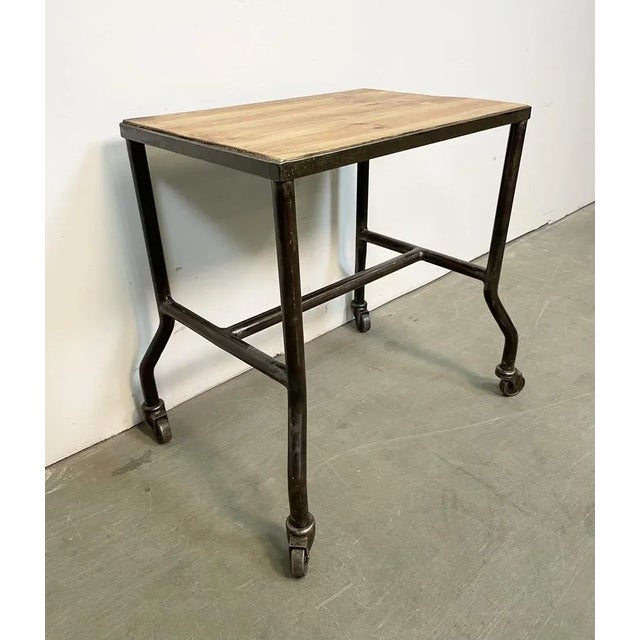 Industrial table from the 1960s. It features an iron construction,a four original wheels and a solid wooden plate. The...