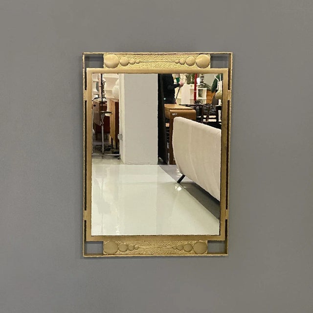 Italian modern wall mirror in golden metal with geometric decorations, 1980s Rectangular wall mirror. It features a gold...