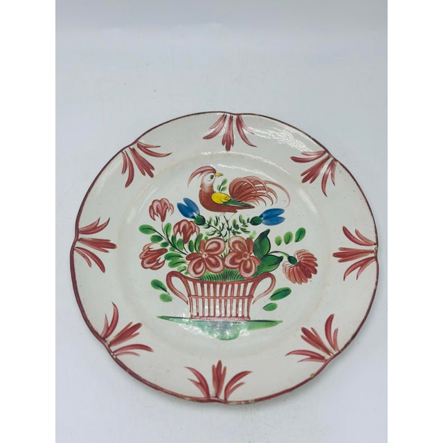 This is a hand-painted earthenware plate with a charming folk-art floral and bird motif, likely intended as a decorative...