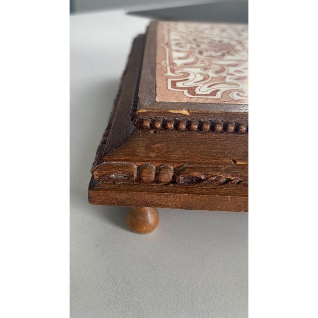 Elegant vintage trivet made from an antique brown and cream floral-patterned earthenware tile, mounted on a carved wooden...