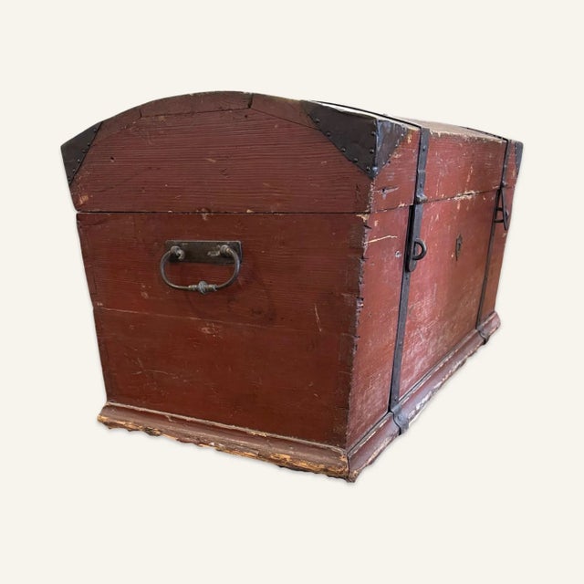 This early American chest is wood, painted red, with iron hardware. The handles are wrought iron and the banding and...