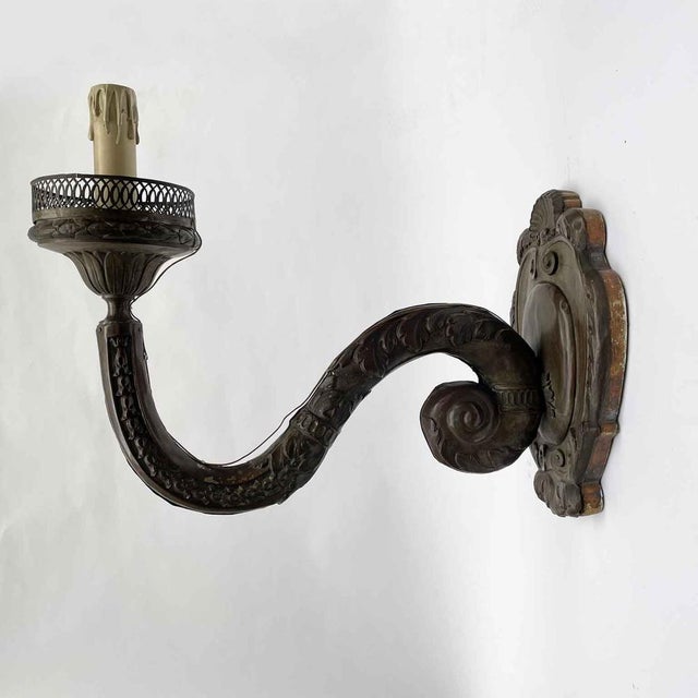 A pair of 18th-century embossed copper arms, mounted on a carved poplar wood core and silvered along the base edge. In...