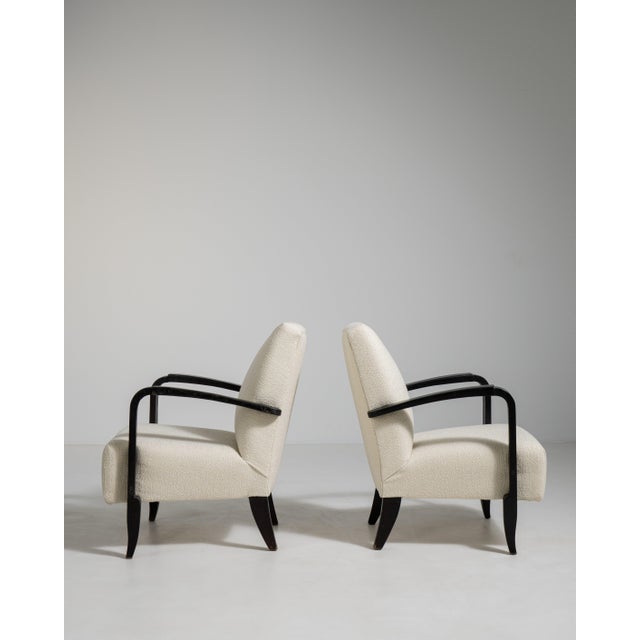 A pair of armchairs influenced by late Art Deco styling, with rounded forms and a focus on comfort. The streamlined shapes...