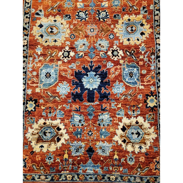 This elegantly designed rug showcases a contemporary floral pattern in vibrant blue and goldenrod hues set against a rich...