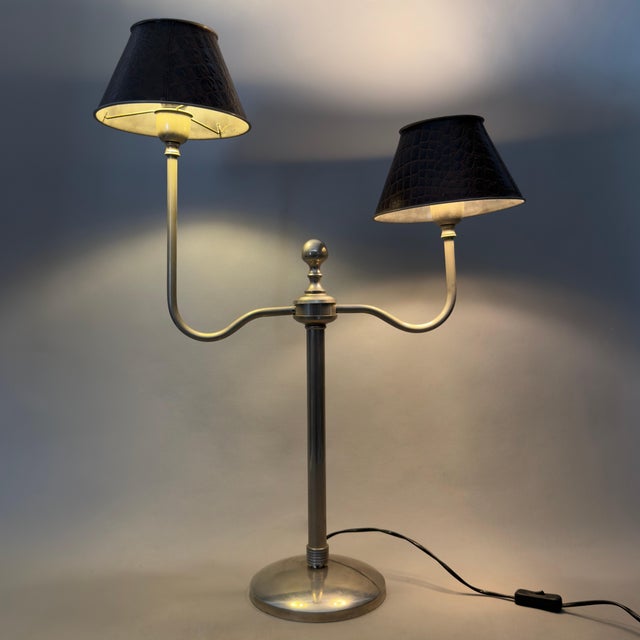 An elegant and dramatic two-armed table lamp in mid-century style, attributed to a 1970s design. Subject and Style:...
