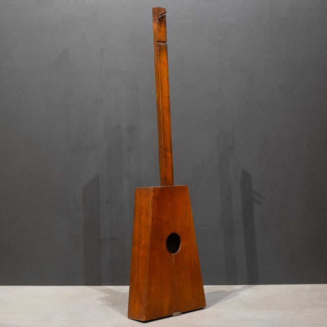 ABOUT A vintage, wooden guitalin. The guitalin features a distinct trapezoidal body and typically has four courses of...
