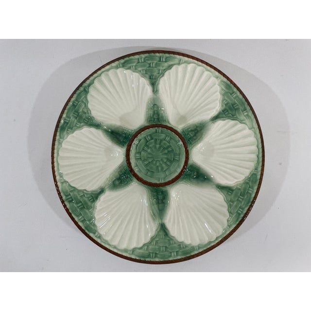A charming French Faience Longchamp glazed majolica oyster plate with a lighter green basket weave background trimmed with...