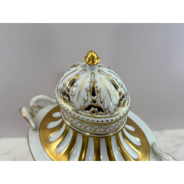 This elegant antique Dresden porcelain urn vase features finely sculpted figural ram handles and a delicately reticulated...