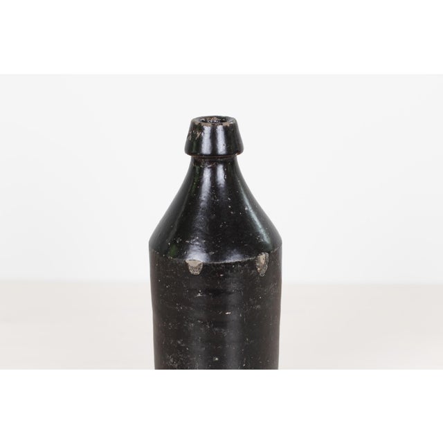 Antique 19th century American stoneware bottle in a rich manganese or Albany slip glaze, with a classic cylindrical form,...
