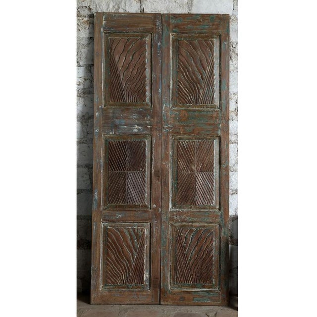 A striking pair of vintage carved closet doors handcrafted from reclaimed wood, featuring an intricate blue floral motif...