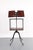 Victorian style dark toned wood library bookstand with a storage shelf on a four legged iron base with caster wheels. The...