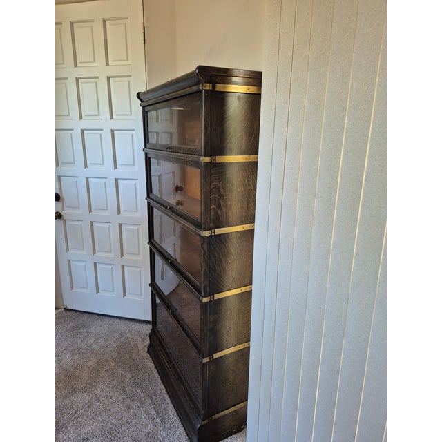 This is an antique Globe-Wernicke wooden barrister bookcase featuring a modular design with four stackable glass-front...