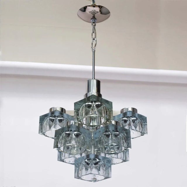 A Lightolier chandelier by Italian designer Gaetano Sciolari. It features nine glass shades with polished nickel body.