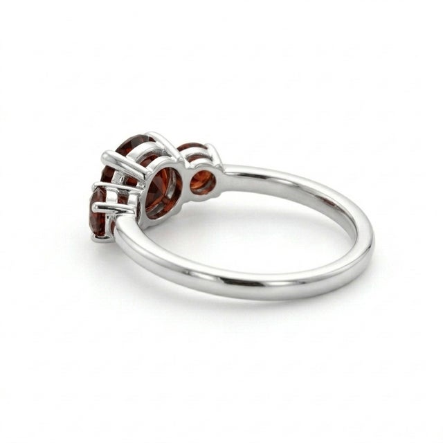 This elegant ring features a timeless trio of Garnet gemstones, admired for their deep red hue and rich, captivating...