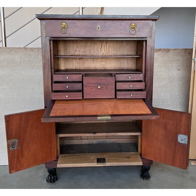 A dramatic Charles X fall front secretary in astounding burled mahogany veneer. The original fossilized marble top is...