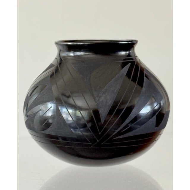 A black glazed earthenware pot. From Mata Ortiz in Northern Mexico. Signed on underside Tomasa Mora. Circa 1990.