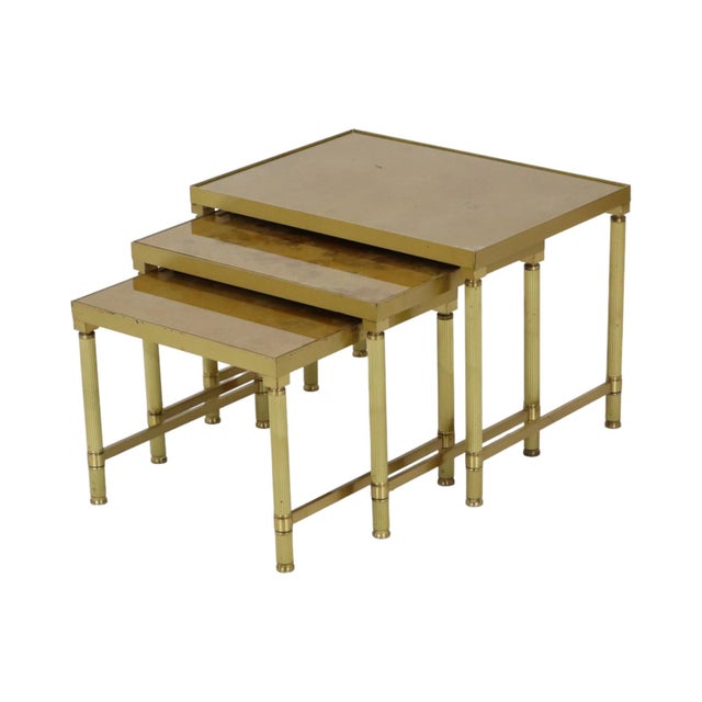 Vintage set of three nesting tables of graduated sizes, featuring brass frames and gold-toned glass tops with a marble...