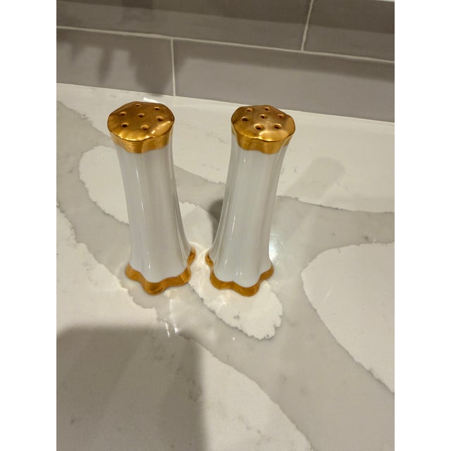 Lovely white porcelain salt & pepper shakers. Love this style with gold tops and around the bottom! Newer plastic stoppers.