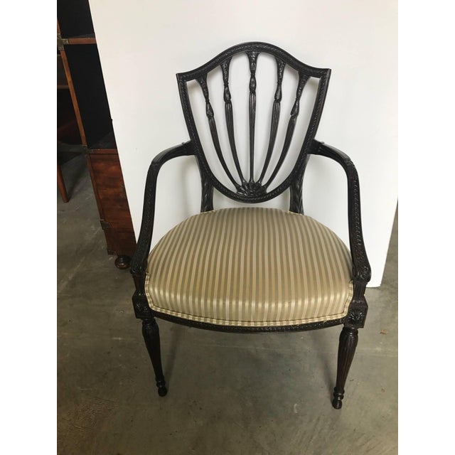 Elegant and graceful hand carved mid-19th century shield back Hepplewhite armchair. The dark mahogany frame is expertly...