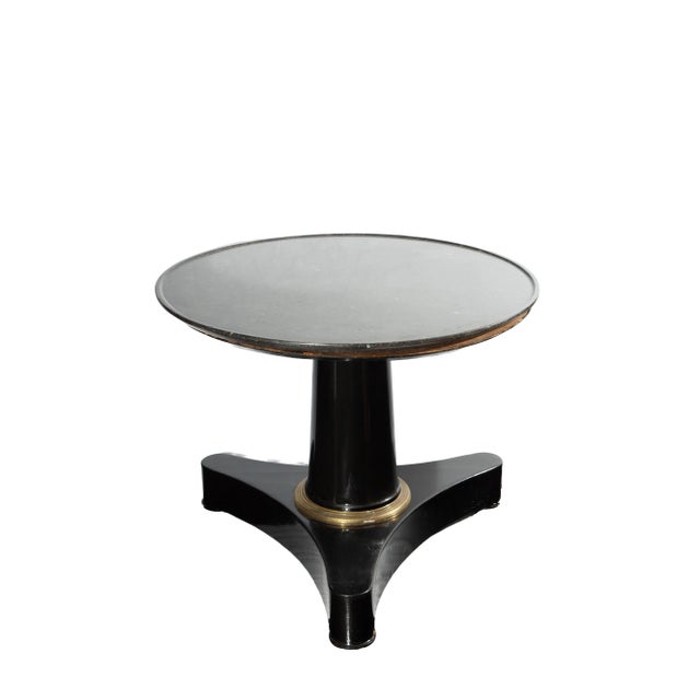 A 19th-century black lacquer pedestal table featuring a circular fossil-stone tabletop and gilt-bronze (ormolu) decorative...