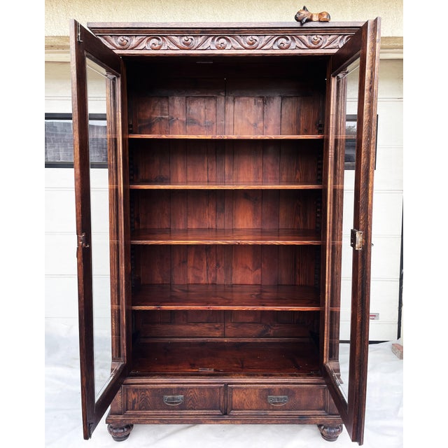 An antique bookcase/display cabinet made of solid oak and pine, dating back to the early 20th century and featuring an...