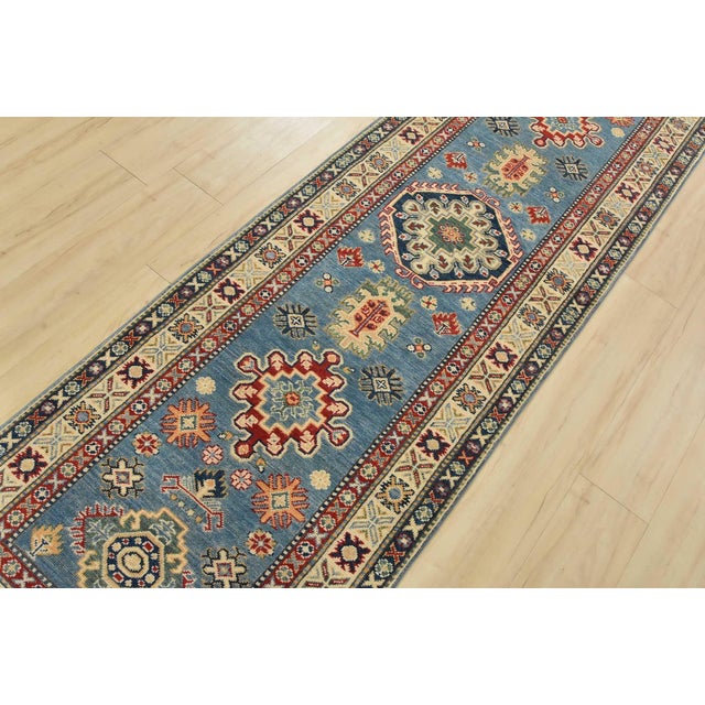 A tribal Caucasian Kazak runner hand-knotted with fine wool on a cotton foundation. This rug features a row of medallions...